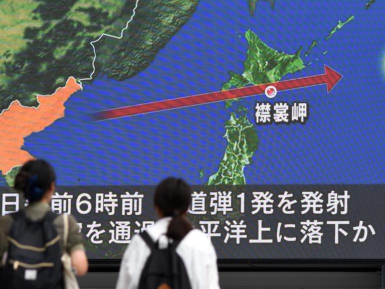Zwei Personen in Japan verfolgen die Berichterstattung über den nordkoreanischen Raketen auf einem Monitor.
