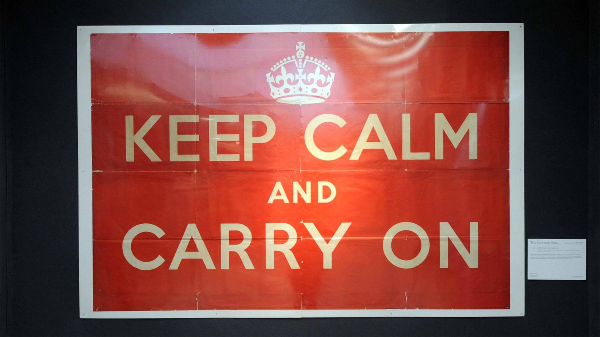 Zu sehen ist ein Propaganda-Poster, das 1939 von der britischen Regierung produziert wurde. Die Aufschrift lautet Keep Calm and Carry On (ruhig bleiben und weitermachen)