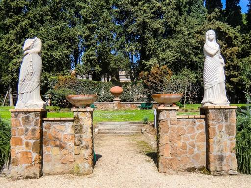 Blick in einen Teil des Gartens der Villa Massimo, der mit zwei nur teilweise erhaltenen, weißen Frauen-Marmorfiguren geschmückt ist.