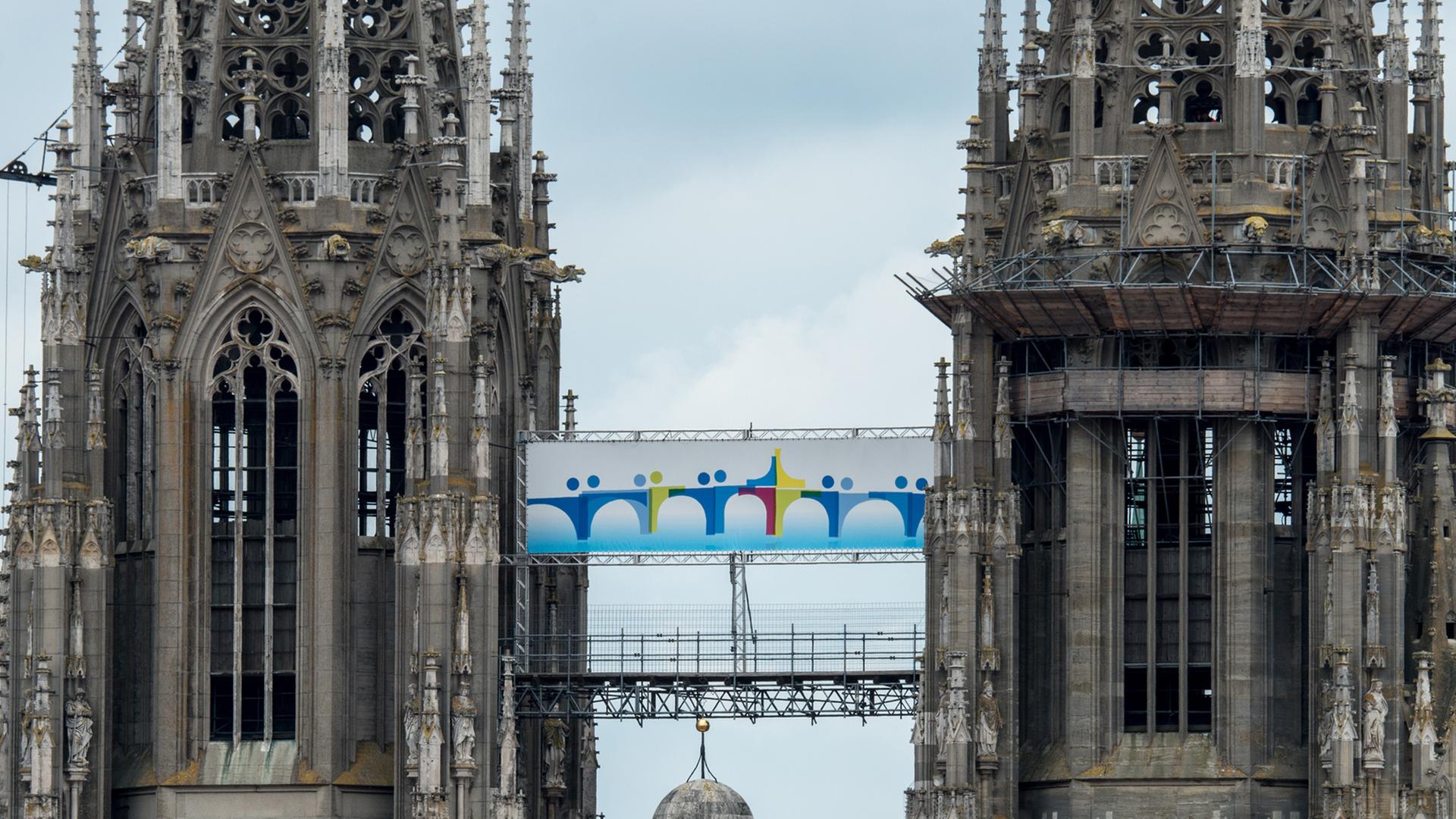 Ein Plakat mit dem Logo des Katholikentages hängt am 27.05.2014 zwischen den Türmen des Doms St. Peter in Regensburg (Bayern).