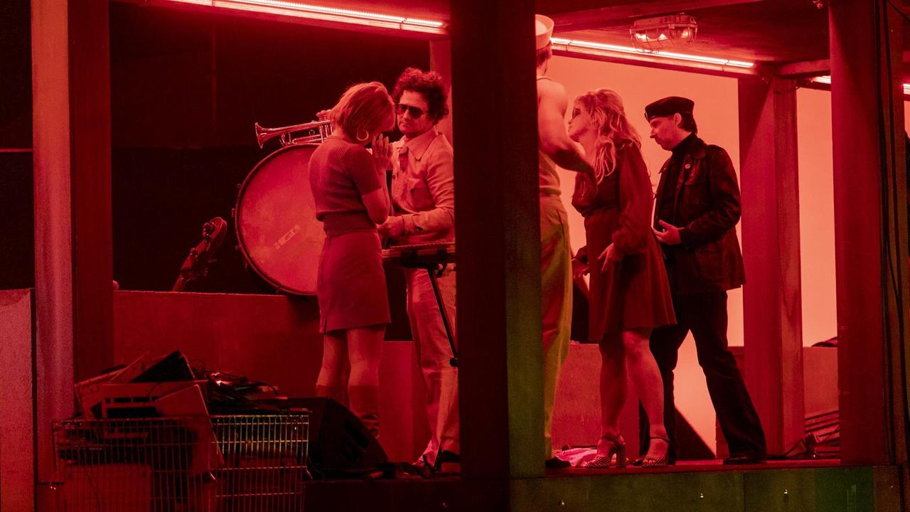 Vier Personen stehen auf einer Party in dämmrig-rötlichem Licht herum. Vier Personen stehen auf einer Party in dämmrig-rötlichem Licht herum.