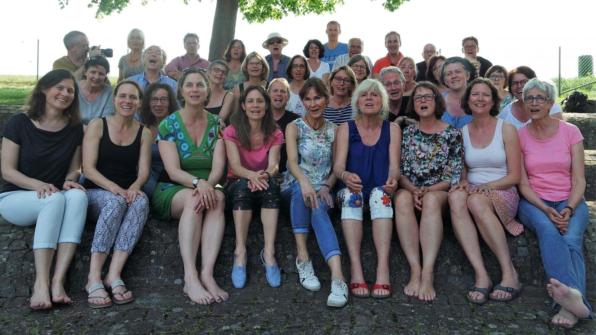 Gruppenbild sitzend unter einem Baum Gruppenbild sitzend unter einem Baum