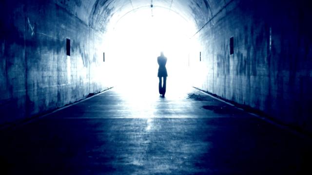 Schattenriss eines Mannes, der durch einen Tunnel ins Licht geht.
