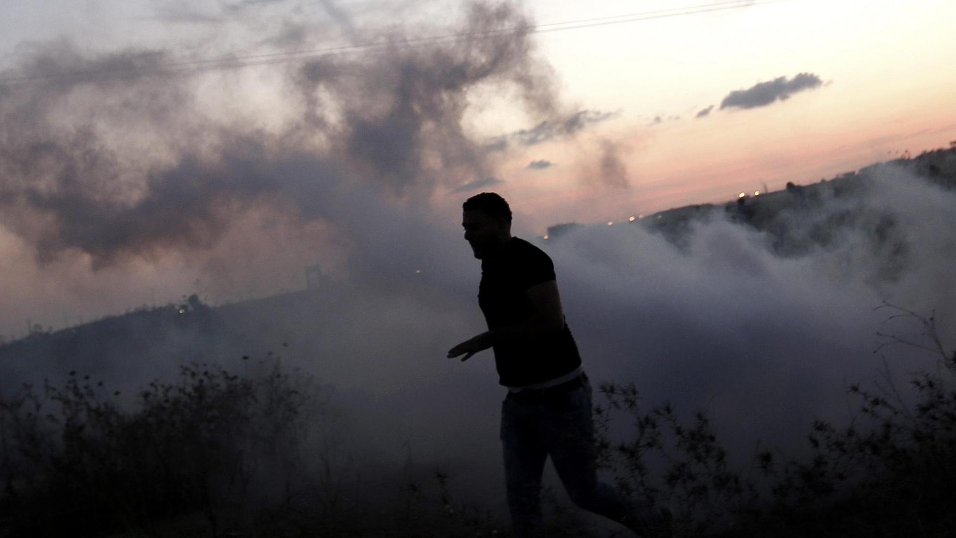 Ein palästinensischer Jugendlicher rennt während eines Zusammenstoßes mit israelischen Truppen nahe Gaza Stadt vor einer Tränengaswolke davon. Ein palästinensischer Jugendlicher rennt während eines Zusammenstoßes mit israelischen Truppen nahe Gaza Stadt vor einer Tränengaswolke davon.