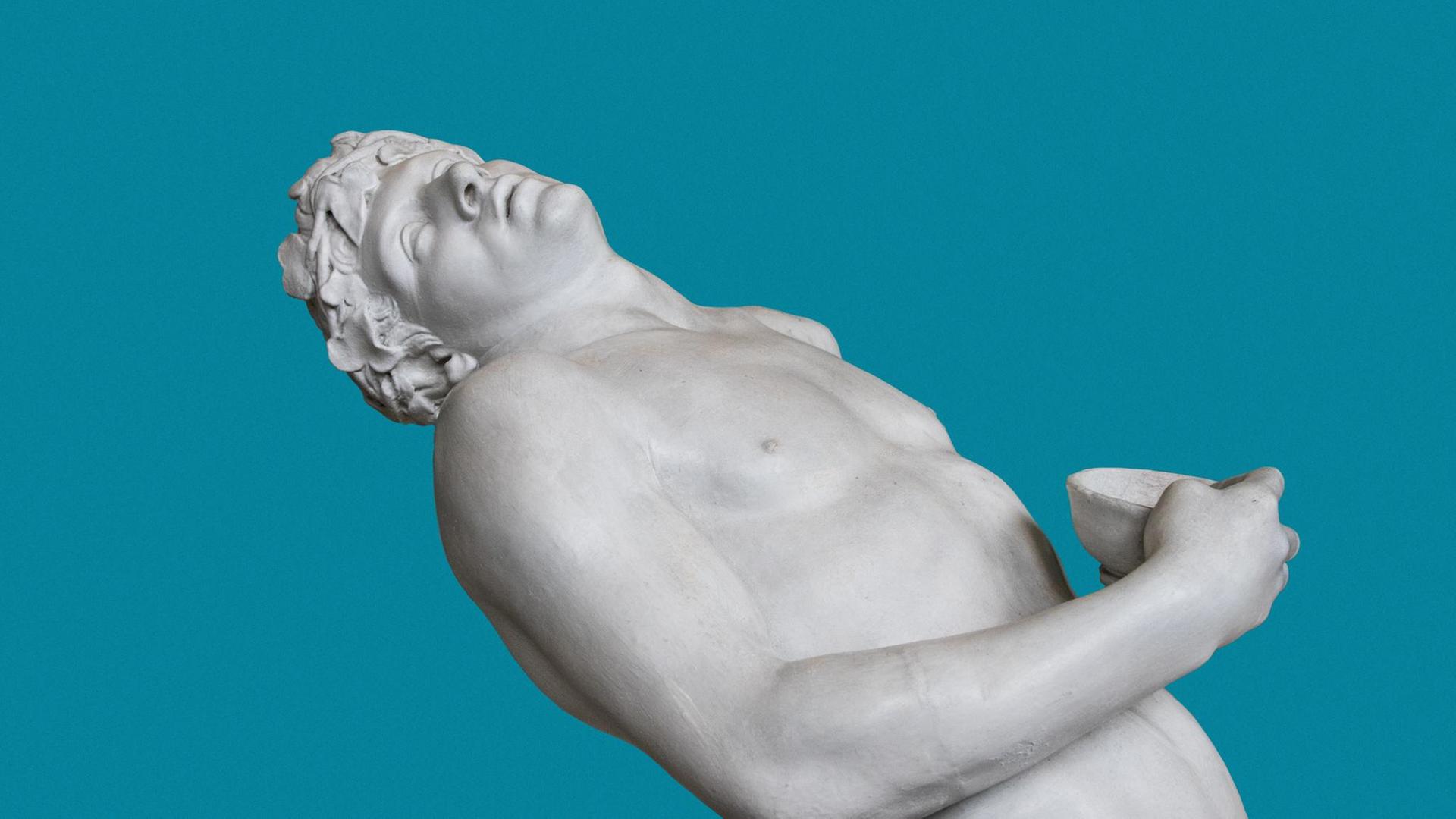 Eine sich nach hinten lehnende, antike männliche Statue vor blauem Hintergrund.