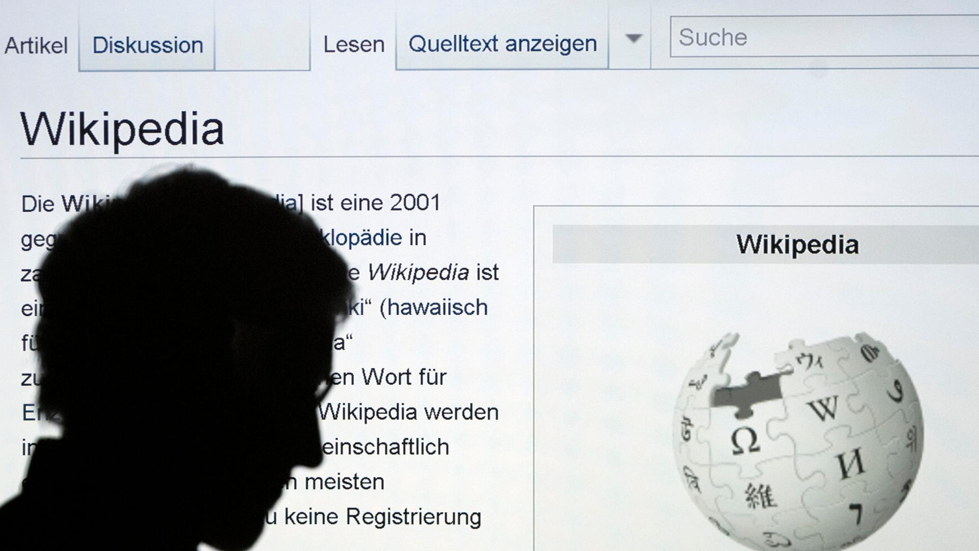 Die Silhouette eines Mannes, der mit seinem Finger auf das Wort Wikipedia zeigt, ist vor der Internetseite der Online-Enzyklopädie Wikipedia zu sehen. Die Silhouette eines Mannes, der mit seinem Finger auf das Wort Wikipedia zeigt, ist vor der Internetseite der Online-Enzyklopädie Wikipedia zu sehen.