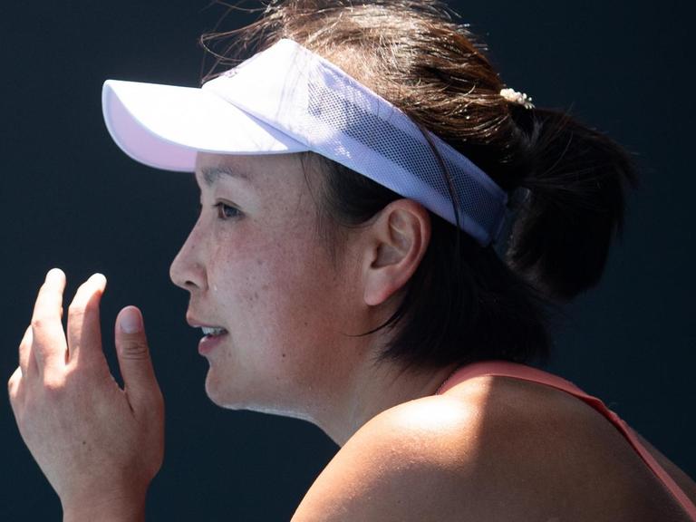 Ein Profilbild der chinesischen Tennisspielerin Peng Shuai. Sie trägt eine Schirmmütze und hält ihre linke Hand vor das Gesicht.
