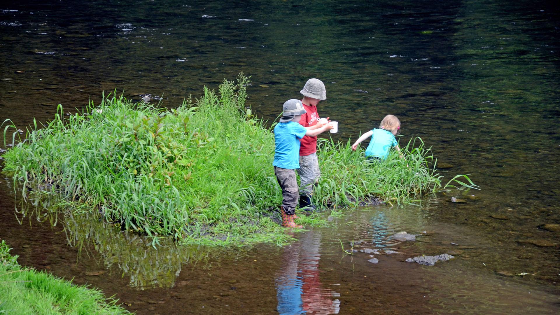 Drei Kinder stehen auf einer kleinen Grasinsel in der Wupper im Brückenpark unter der Müngstener Brücke in Solingen (Nordrhein-Westfalen). (Foto vom 25.05.2014) Drei Kinder stehen auf einer kleinen Grasinsel in der Wupper im Brückenpark unter der Müngstener Brücke in Solingen (Nordrhein-Westfalen). (Foto vom 25.05.2014)