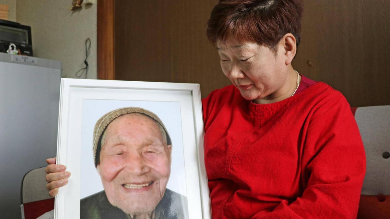 Mieko Okubo hält ein Foto ihres Schwiegervaters Fumio Okubo in die Kamera - der 102-Jährige hatte im April 2011 angesichts einer Evakuierungs-Anordnung Suizid verübt. Mieko Okubo hält ein Foto ihres Schwiegervaters Fumio Okubo in die Kamera - der 102-Jährige hatte im April 2011 angesichts einer Evakuierungs-Anordnung Suizid verübt.