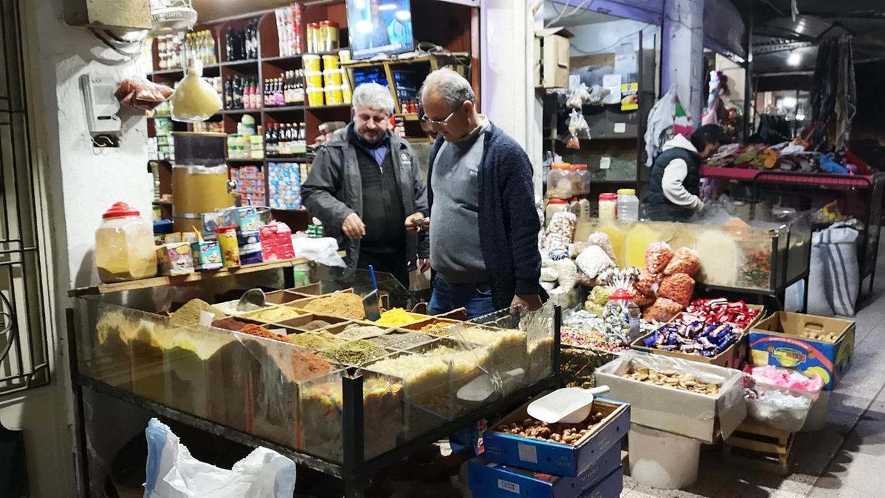 Auf einem Basar im Frühjahr 2019 in der nordsyrischen Stadt Dêrik. Zwei Männer stehen vor einem Geschäft, wo Gewürze und andere Lebensmittelverkauft werden. Auf einem Basar im Frühjahr 2019 in der nordsyrischen Stadt Dêrik. Zwei Männer stehen vor einem Geschäft, wo Gewürze und andere Lebensmittelverkauft werden.