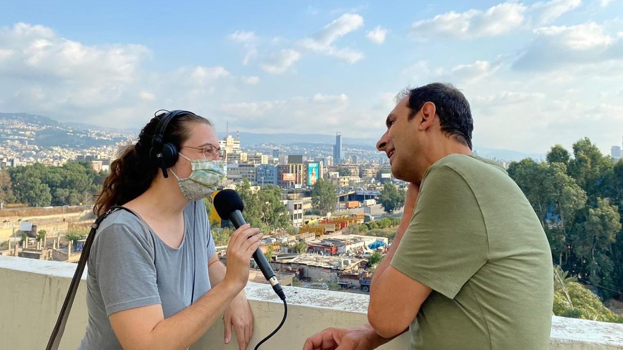 Die Autorin im Gespräch mit dem Künstler Marwan Rechmaoui. Hinter ihnen ist die Kulisse von Beirut sichtbar.