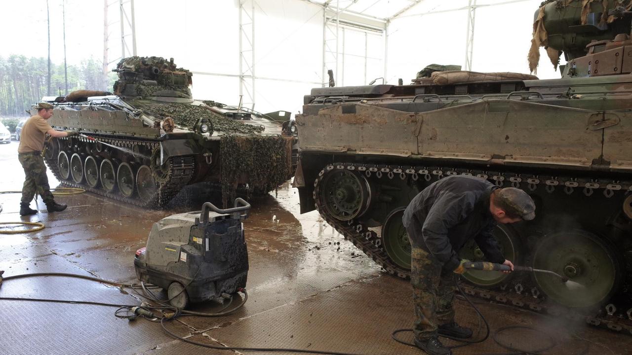Soldaten reinigen nach der Übung einen Schützenpanzer Soldaten reinigen nach der Übung einen Schützenpanzer
