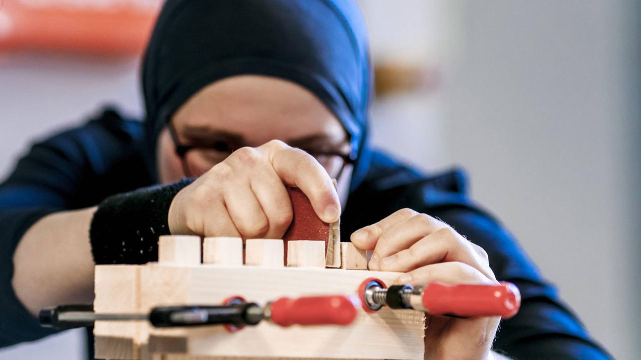 Eine gefluechtete Frau arbeitet in der Übungswerkstatt für Handwerksausbildung der Initiative Arrivo der Handwerkskammer Berlin.