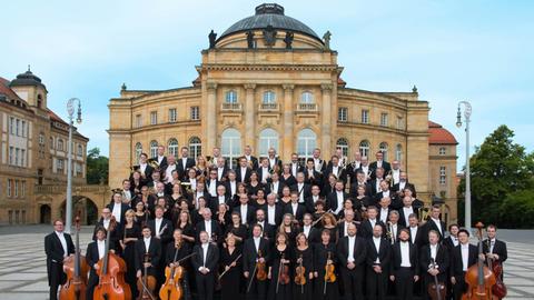 Das Orchester hat sich vorm historischen Opernhaus der Stadt versammelt