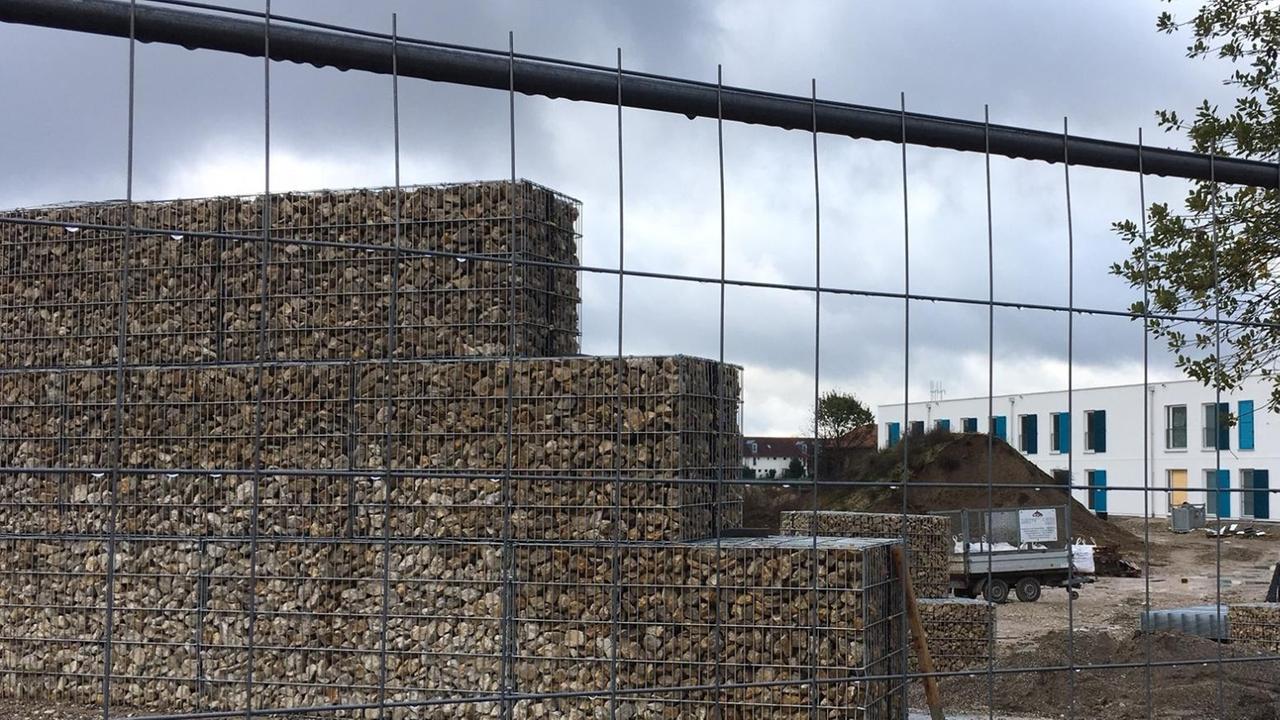 Eine Lärmschutzwand ist in München (Bayern) auf der Baustelle für eine Flüchtlingsunterkunft zu sehen. Anwohner hatten die Mauer als Lärmschutz im Stadtteil Neuperlach durchgesetzt. Die Unterkunft für jugendliche Flüchtlinge ist noch nicht in Betrieb. Eine Lärmschutzwand ist in München (Bayern) auf der Baustelle für eine Flüchtlingsunterkunft zu sehen. Anwohner hatten die Mauer als Lärmschutz im Stadtteil Neuperlach durchgesetzt. Die Unterkunft für jugendliche Flüchtlinge ist noch nicht in Betrieb.