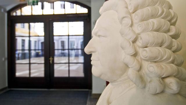In einem historischen Hof mit grozügiger Eingangspassage steht die weiße Büste Johann Sebastian Bachs mit der typischen barocken Locken-Perrücke.