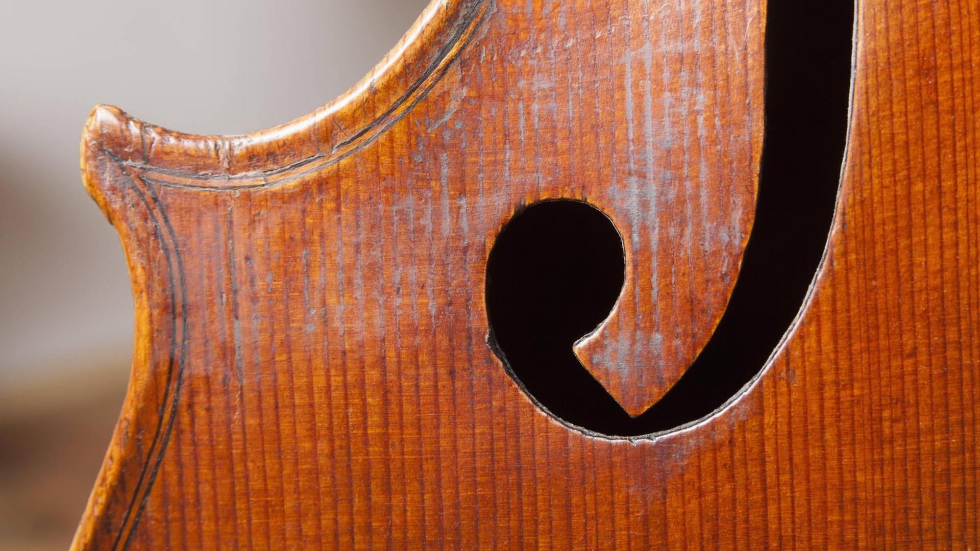 Detailaufnahme einer alten Geige, mit Fokus auf eines der Schalllöcher. Detailaufnahme einer alten Geige, mit Fokus auf eines der Schalllöcher.