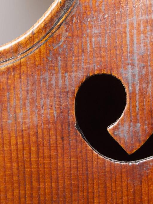 Detailaufnahme einer alten Geige, mit Fokus auf eines der Schalllöcher.