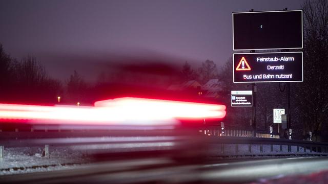 Ein Auto fährt an einem Schild vorbei, das auf den Feinstaub-Alarm in Stuttgart hinweist.