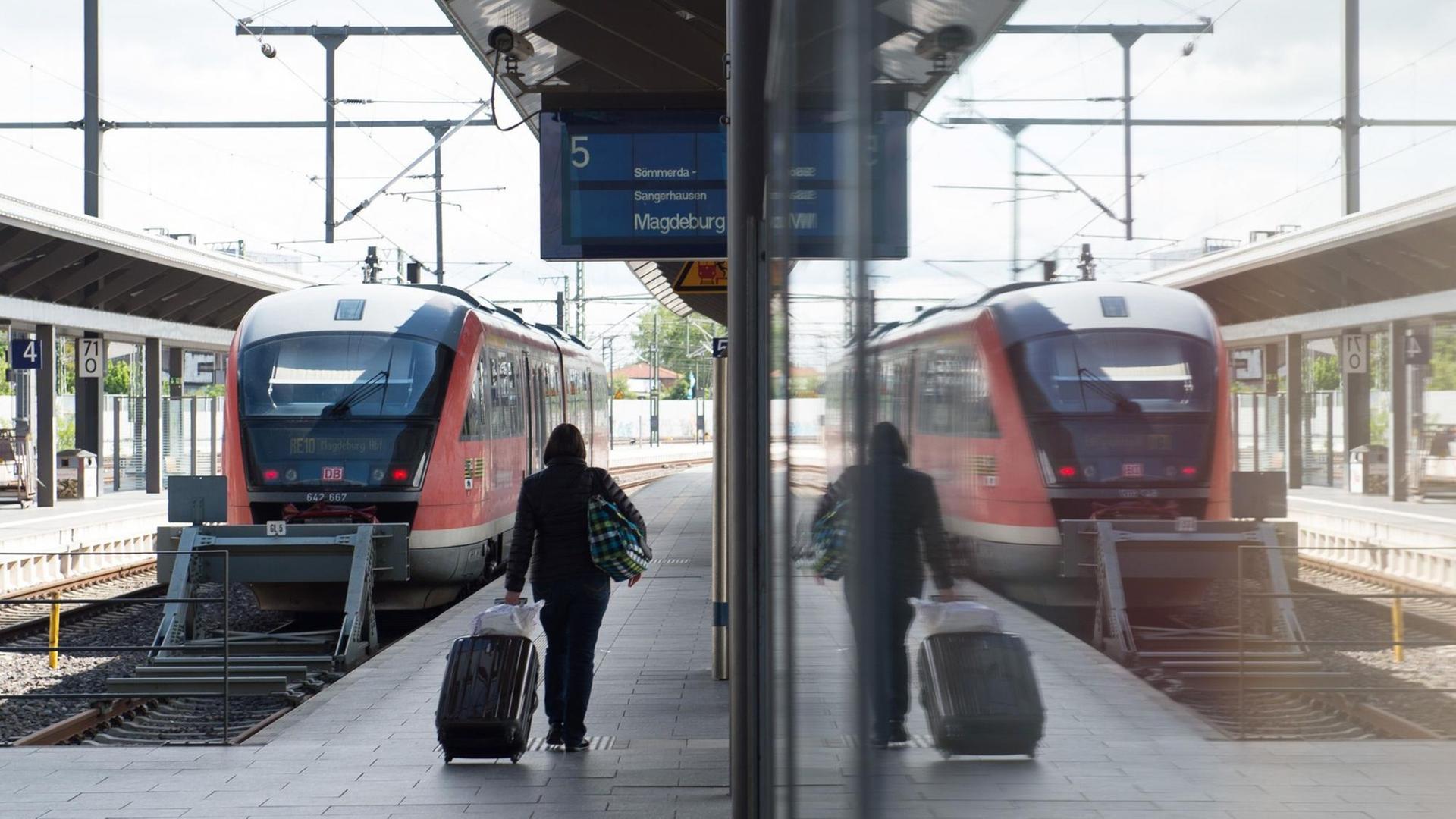 Eine Frau läuft mit einem Koffer über den Bahnsteig. Eine Frau läuft mit einem Koffer über den Bahnsteig.