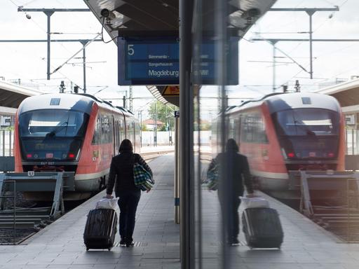 Eine Frau geht am 19.05.2015 am Hauptbahnhof in Erfurt (Thüringen) auf einem Bahnsteig entlang und spiegelt sich in einer Scheibe.