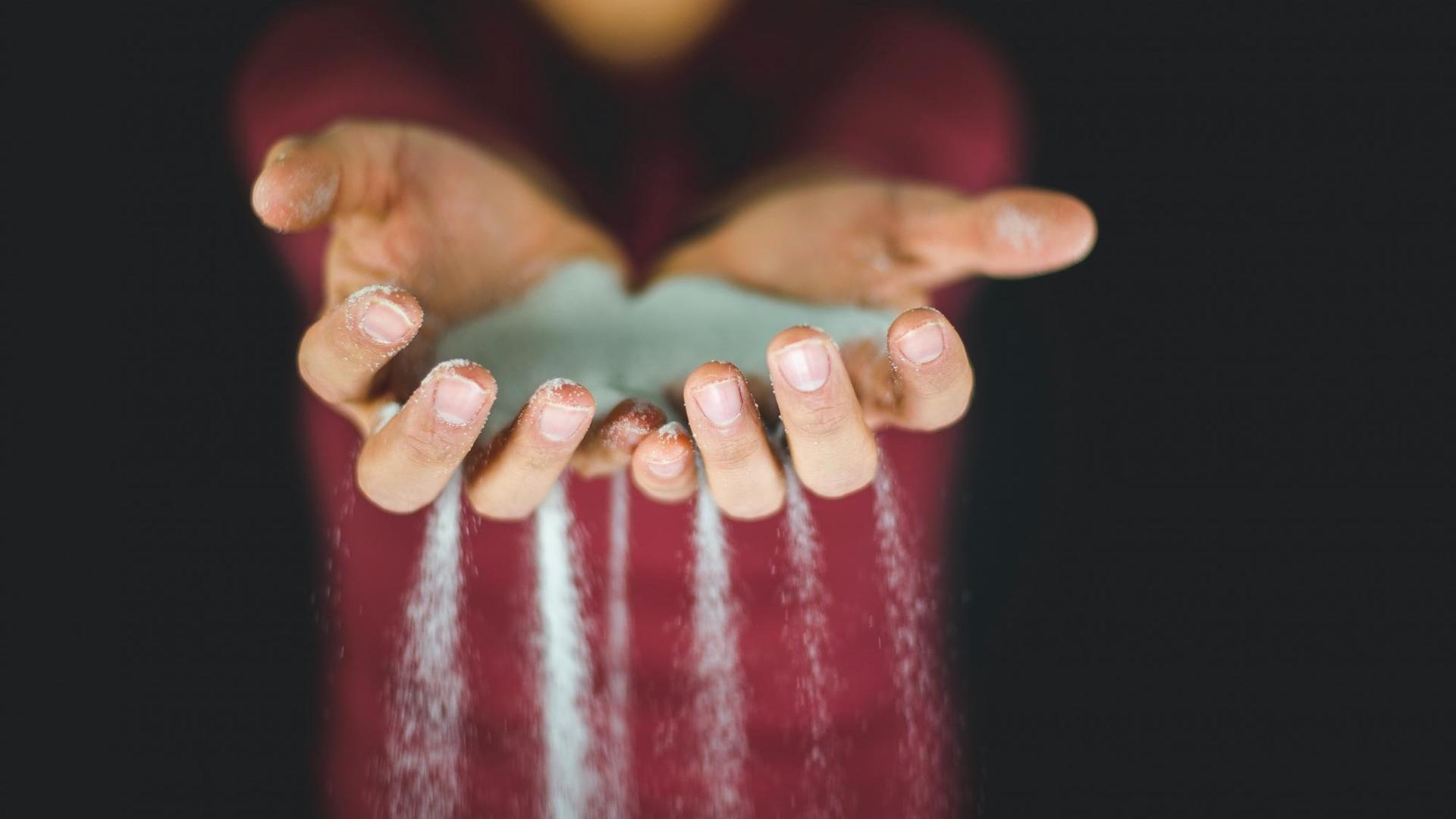 Blauer Sand rieselt durch die Finger ausgestreckter Hände. Blauer Sand rieselt durch die Finger ausgestreckter Hände.