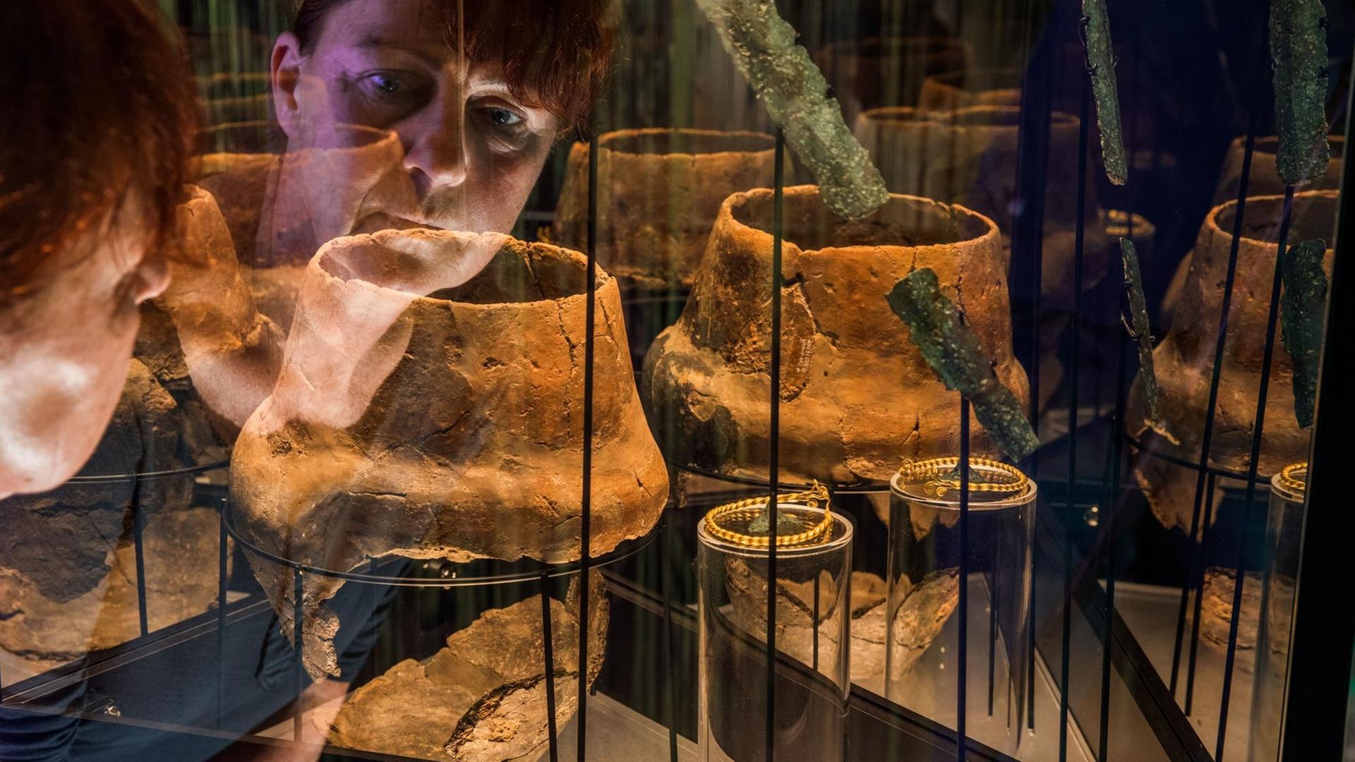 Museumsleiterin Heike Pilz schaut in eine Vitrine mit Grabausstattungen aus der Zeit zwischen 1300 - 1100 v. Chr., die am 04.10.2017 in der neuen Ausstellung "Blutiges Gold - Macht und Gewalt in der Bronzezeit" im Museumsgebäude des Archäologischen Freilichtmuseums Groß Raden (Mecklenburg-Vorpommern) in der Nähe von Sternberg zu sehen sind. Museumsleiterin Heike Pilz schaut in eine Vitrine mit Grabausstattungen aus der Zeit zwischen 1300 - 1100 v. Chr., die am 04.10.2017 in der neuen Ausstellung "Blutiges Gold - Macht und Gewalt in der Bronzezeit" im Museumsgebäude des Archäologischen Freilichtmuseums Groß Raden (Mecklenburg-Vorpommern) in der Nähe von Sternberg zu sehen sind.