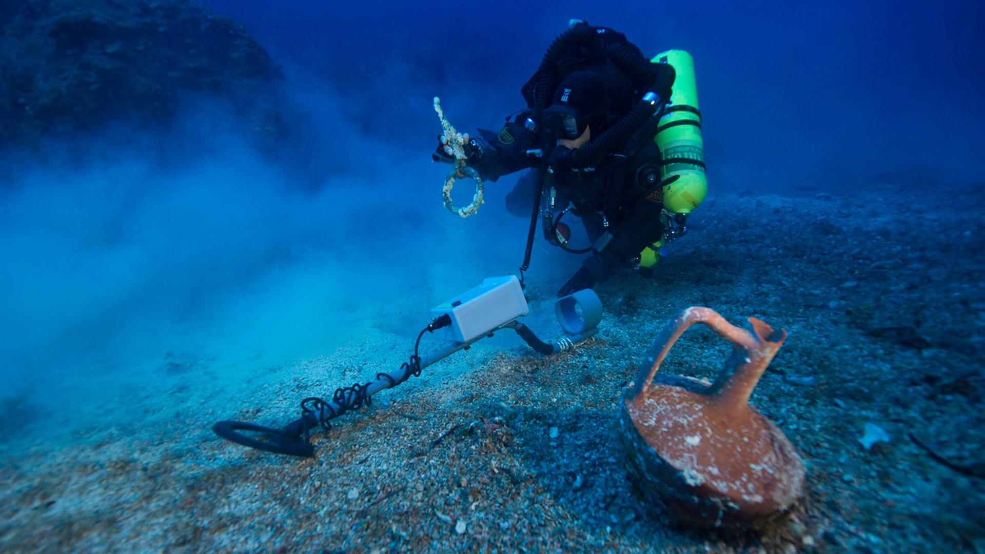 Ein Taucher vor einem fast unversehrten Krug in der Nähe der Insel Antikythera in Griechenland während einer Erkundung der Stelle, an dem das berühmte Schiff Antikythera gesunken war. Ein Taucher vor einem fast unversehrten Krug in der Nähe der Insel Antikythera in Griechenland während einer Erkundung der Stelle, an dem das berühmte Schiff Antikythera gesunken war.