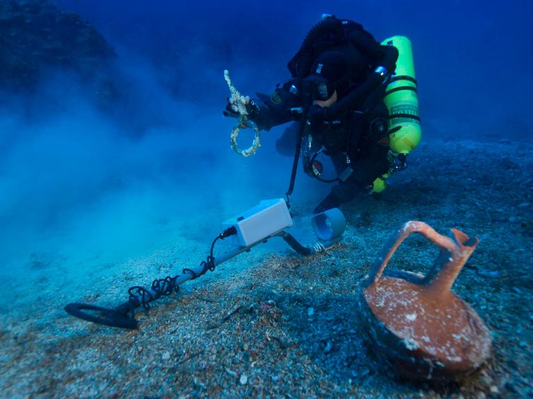 Ein Taucher vor einem fast unversehrten Krug in der Nähe der Insel Antikythera in Griechenland während einer Erkundung der Stelle, an dem das berühmte Schiff Antikythera gesunken war.