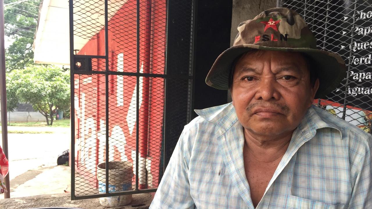 Santos, der 56-jährige Ortega-Unterstützer und Profiteur der Regierung, sitzt vor seinem kleinen Haus mit Wellblechdach. Santos, der 56-jährige Ortega-Unterstützer und Profiteur der Regierung, sitzt vor seinem kleinen Haus mit Wellblechdach.
