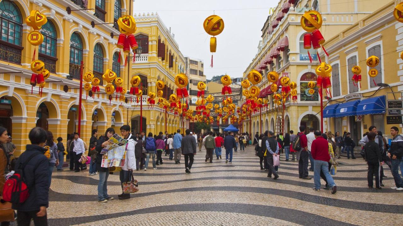 Menschen flanieren über den geschmückten Leal-Senado-Platz in Macau im Süden Chinas, mit seinem typisch portugiesischen Pflaster 
