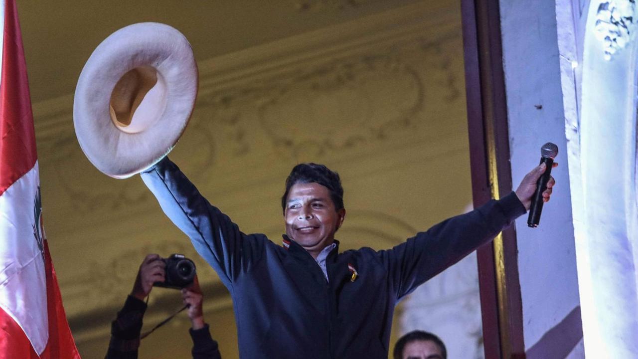 Ein Mann in dunkler Jacke steht mit emporgereckten Armen jubelnd auf einem Balkon. In der einen Hand hält er ein Mikrofon, in der anderen einen hellen Sombrero. Ein Mann in dunkler Jacke steht mit emporgereckten Armen jubelnd auf einem Balkon. In der einen Hand hält er ein Mikrofon, in der anderen einen hellen Sombrero.