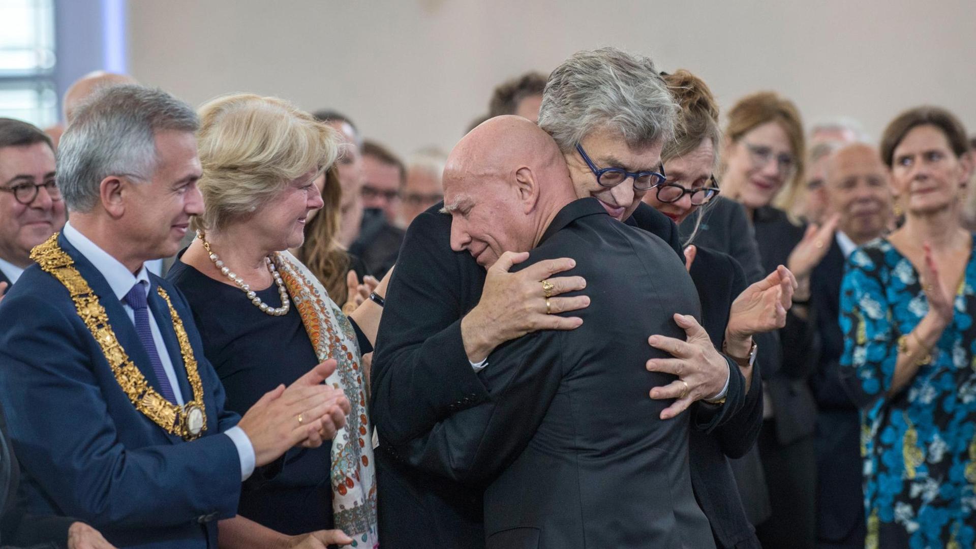 Sebastião Salgado umarmt seinen Laudator Wim Wenders. Daneben stehen Frankfurts Oberbürgermeister Peter Feldmann und Kulturstaatsministerin Monika Grütters.