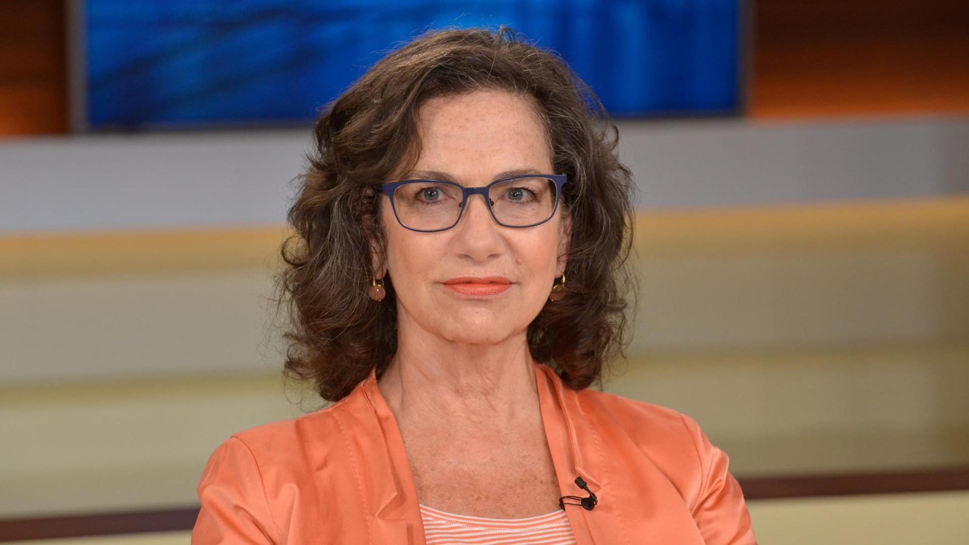 Susan Neiman, in einem lachsrosa Sakko, sitzt in einem Fernsehstudio und schaut konzentriert in Richtung eines Gesprächspartners außerhalb des Bildes. Susan Neiman, in einem lachsrosa Sakko, sitzt in einem Fernsehstudio und schaut konzentriert in Richtung eines Gesprächspartners außerhalb des Bildes.