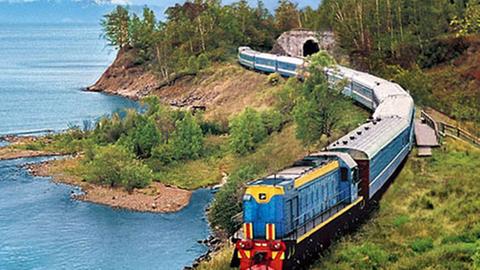 Ein Zug auf der Strecke der Transsibirischen Eisenbahn fährt entlang des Baikalsees