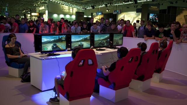 Auf der Gamescom-Messe für Computerspiele spielen Jugendliche das Autorennen 'Need for Speed'.