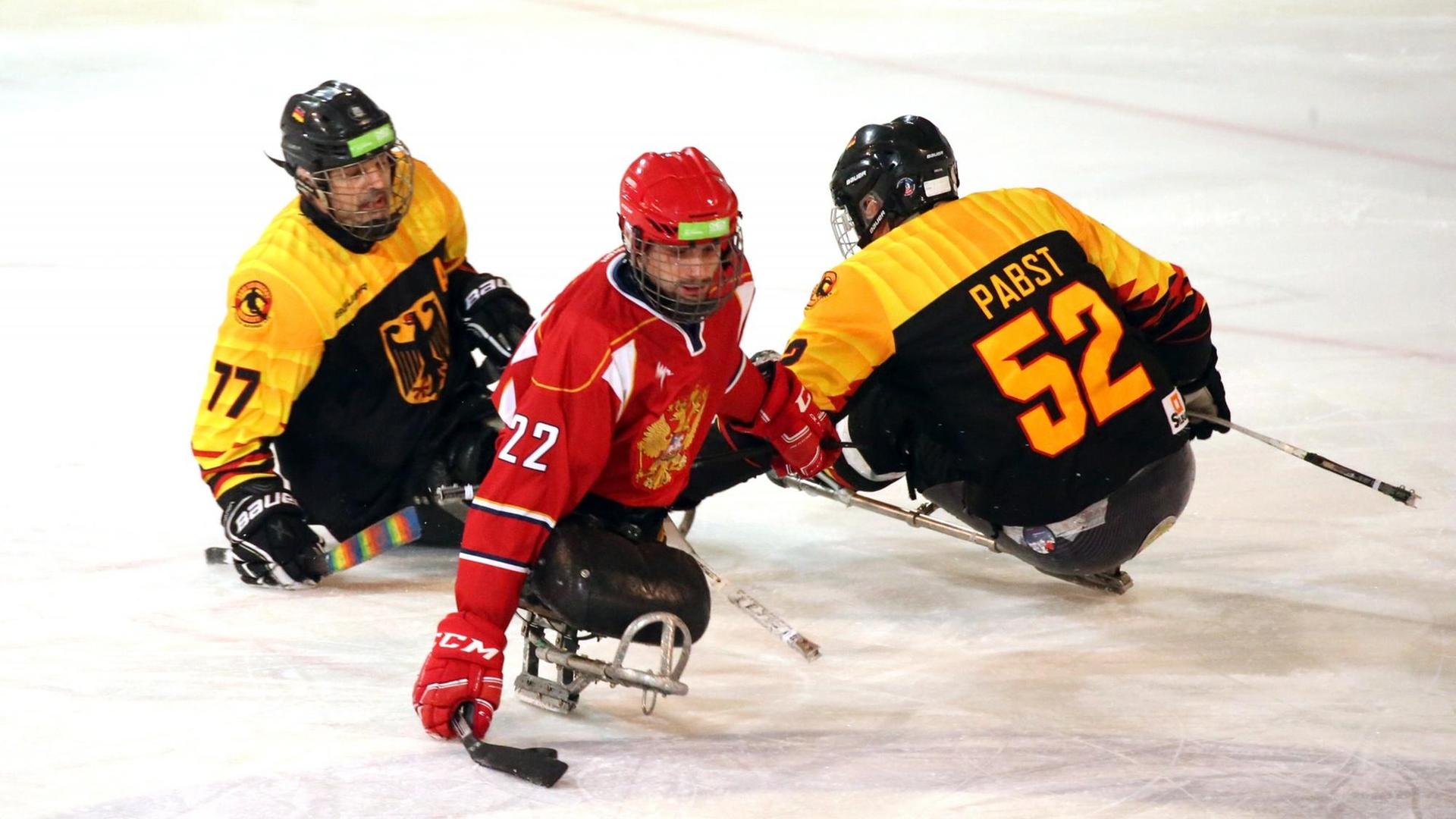 Spielszene auf dem Eis zwischen 2 deutschen und einem russischen Para-Eishockey-Athleten. Spielszene auf dem Eis zwischen 2 deutschen und einem russischen Para-Eishockey-Athleten.