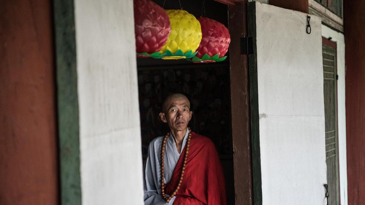 Ein buddhistischer Mönch steht in einer Tür, während er darauf wartet, ausländische Touristen zu begrüßen, die am 20. August 2018 den Pohyon-Tempel in Myohyang, Nordkorea, besuchen. Ein buddhistischer Mönch steht in einer Tür, während er darauf wartet, ausländische Touristen zu begrüßen, die am 20. August 2018 den Pohyon-Tempel in Myohyang, Nordkorea, besuchen.