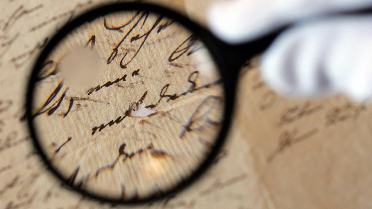 Blick auf einen Autographe, zum Teil durch eine Lupe betrachtet. Blick auf einen Autographe, zum Teil durch eine Lupe betrachtet.