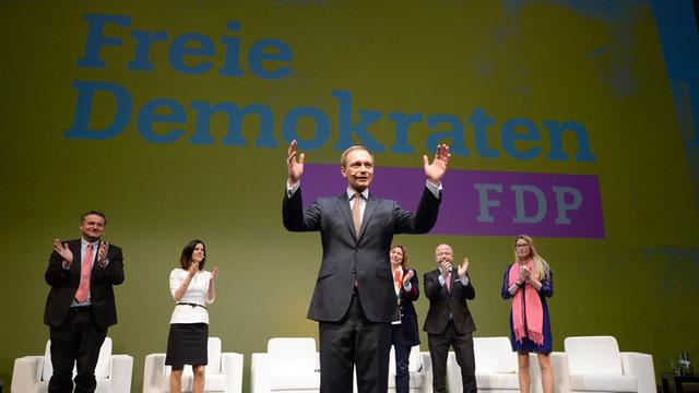 Christian Lindner, der Vorsitzende der FDP, winkt in Stuttgart im Opernhaus beim traditionellen Dreikönigstreffen der Partei nach seiner Rede ins Publikum. Im Hintergrund wird das neue Parteilogo präsentiert.