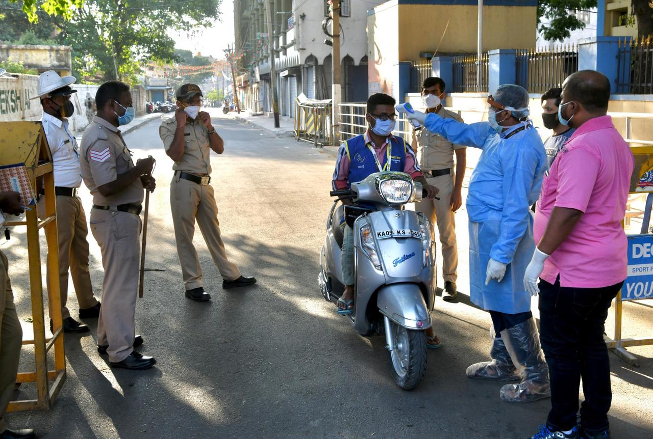 Gesundheitspersonal und Polizei halten in der indischen Stadt Bangalore Passanten an und messen Fieber.