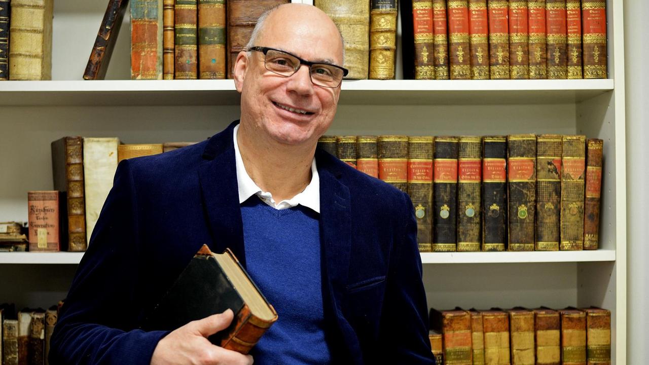 Der Vorstand der Gesellschaft für deutsche Sprache, Peter Schlobinski, steht am 08.12.2016 in Wiesbaden (Hessen) vor einem Bücherregal mit historischen Worterbüchern. Das "Wort des Jahres" 2016 lautet "postfaktisch". Mit dem "Wort des Jahres" wird der Begriff gekürt, der nach Ansicht der Experten die öffentliche Diskussion in den vergangenen Monaten am meisten bestimmte. Foto: Susann Prautsch/dpa | Verwendung weltweit Der Vorstand der Gesellschaft für deutsche Sprache, Peter Schlobinski, steht am 08.12.2016 in Wiesbaden (Hessen) vor einem Bücherregal mit historischen Worterbüchern. Das "Wort des Jahres" 2016 lautet "postfaktisch". Mit dem "Wort des Jahres" wird der Begriff gekürt, der nach Ansicht der Experten die öffentliche Diskussion in den vergangenen Monaten am meisten bestimmte. Foto: Susann Prautsch/dpa | Verwendung weltweit