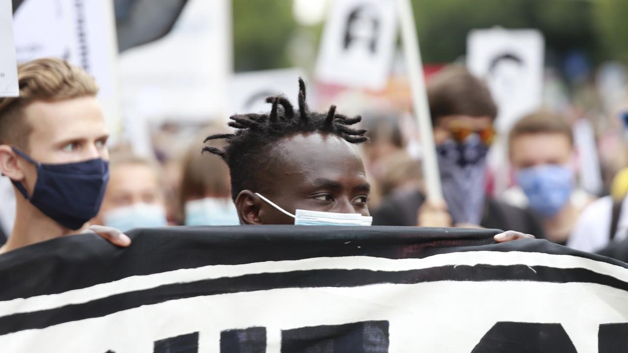 Menschen halten ein Plakat: Demonstration gegen Rassismus, zum Gedenken der Opfer von Hanau. Menschen halten ein Plakat: Demonstration gegen Rassismus, zum Gedenken der Opfer von Hanau.