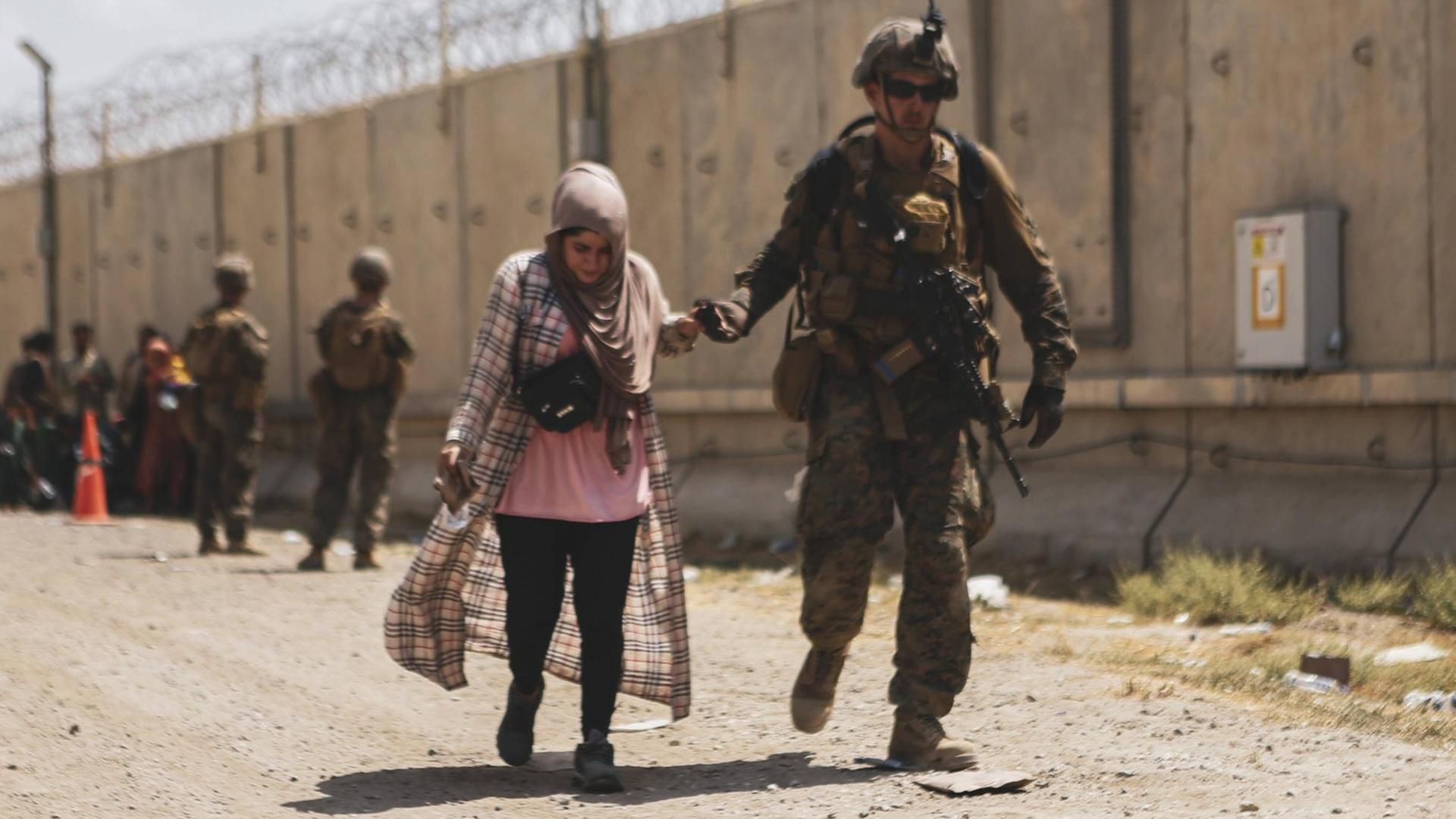 Ein US-Soldat begleitet eine Afghanin am Flughafen Kabul Ein US-Soldat begleitet eine Afghanin am Flughafen Kabul
