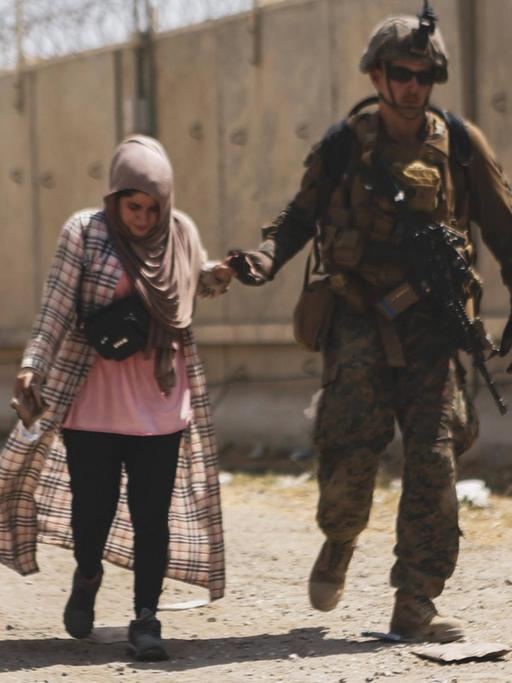 Ein US-Soldat begleitet eine Afghanin am Flughafen Kabul