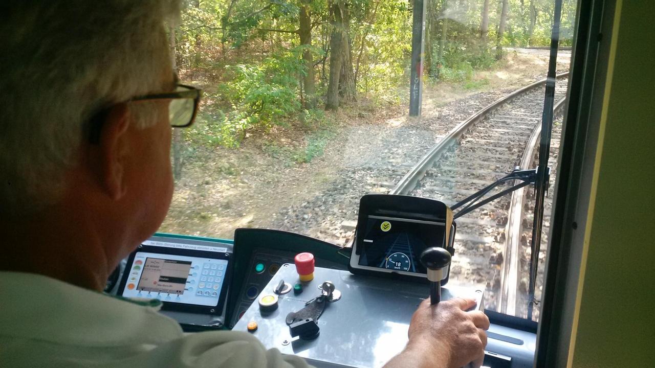 Ein Straßenbahnfahrer blickt durch die Frontscheibe auf die Schienen Ein Straßenbahnfahrer blickt durch die Frontscheibe auf die Schienen