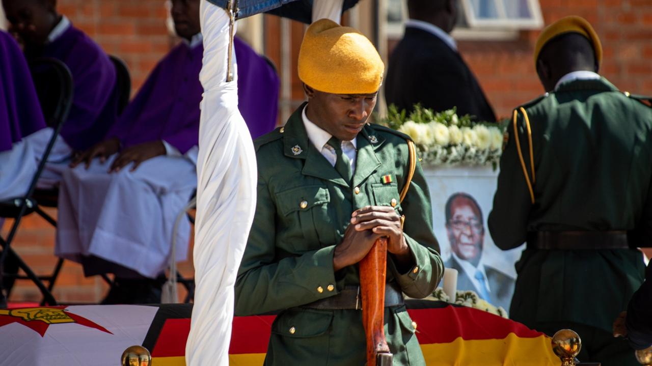 Ein Soldat steht vor einem Sarg, vor dem andere Menschen stehen und Abschied nehmen. Ein Soldat steht vor einem Sarg, vor dem andere Menschen stehen und Abschied nehmen.