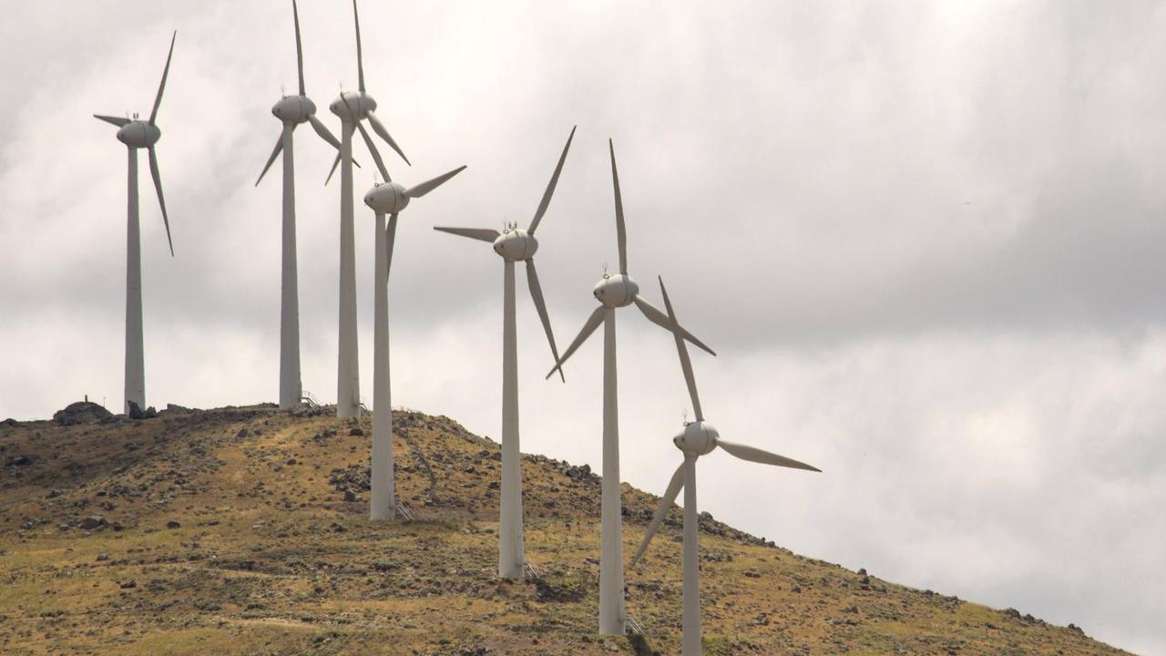 Windkraftanlagen stehen auf Lesbos auf einem kargen Hügel.