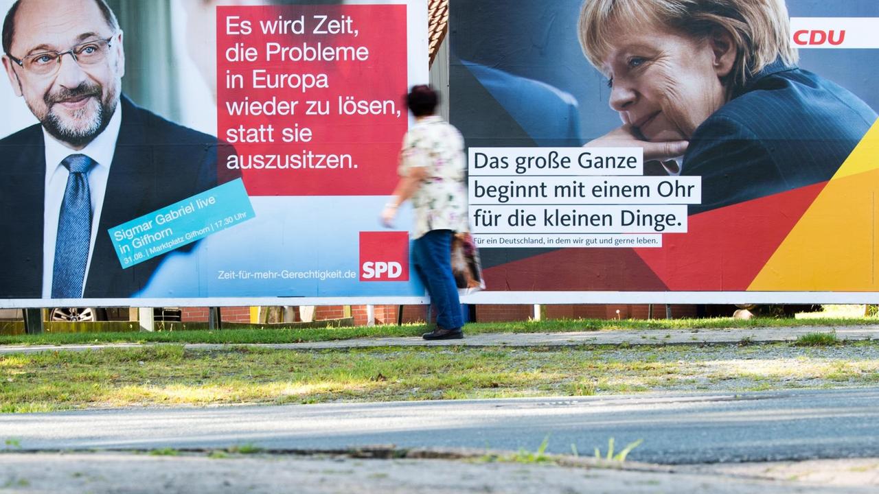 Eine Fußgängerin läuft in Müden (Aller) (Niedersachsen) vorbei an Wahlplakaten von SPD-Kanzlerkandidat Martin Schulz und CDU-Spitzenkandidatin und Bundeskanzlerin Angela Merkel. 