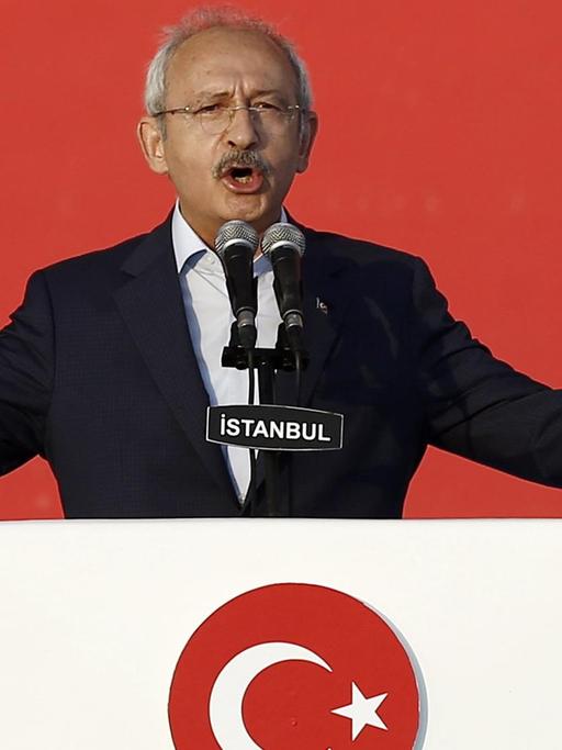 Das Bild zeigt den türkischen Oppositionsführer Kemal Kilicdaroglu, Chef der sozialdemokratischen Partei CHP. Er steht an einem Rednerpult vor rotem Hintergrund.